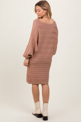 woman wearing a light brown cable knit sweater dress with long sleeves and a relaxed fit