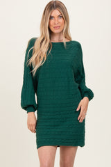 woman wearing a green cable knit sweater dress with balloon sleeves and a relaxed fit
