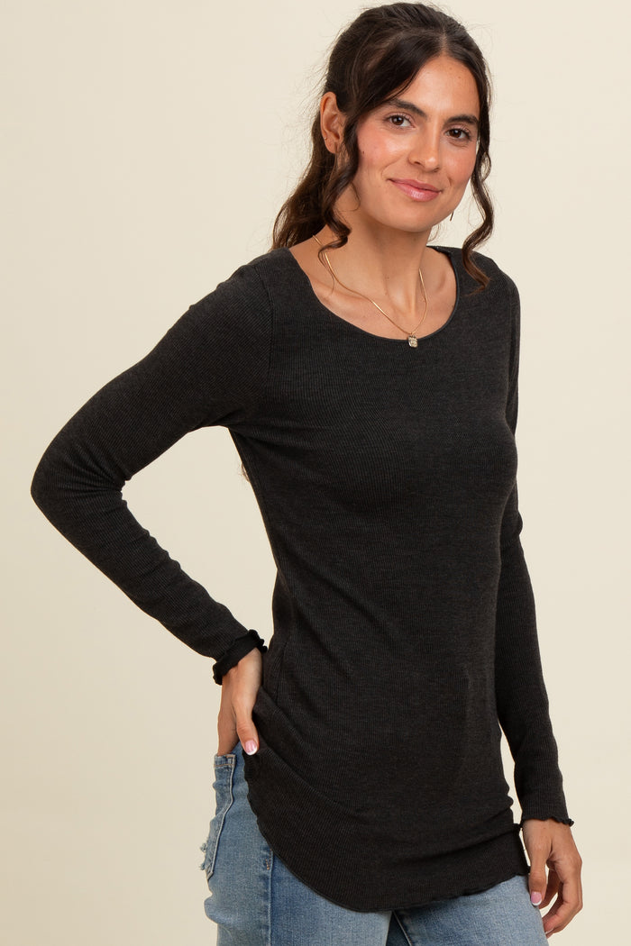 woman wearing a dark gray long sleeve fitted shirt with a scoop neck and ruffle details at the cuffs