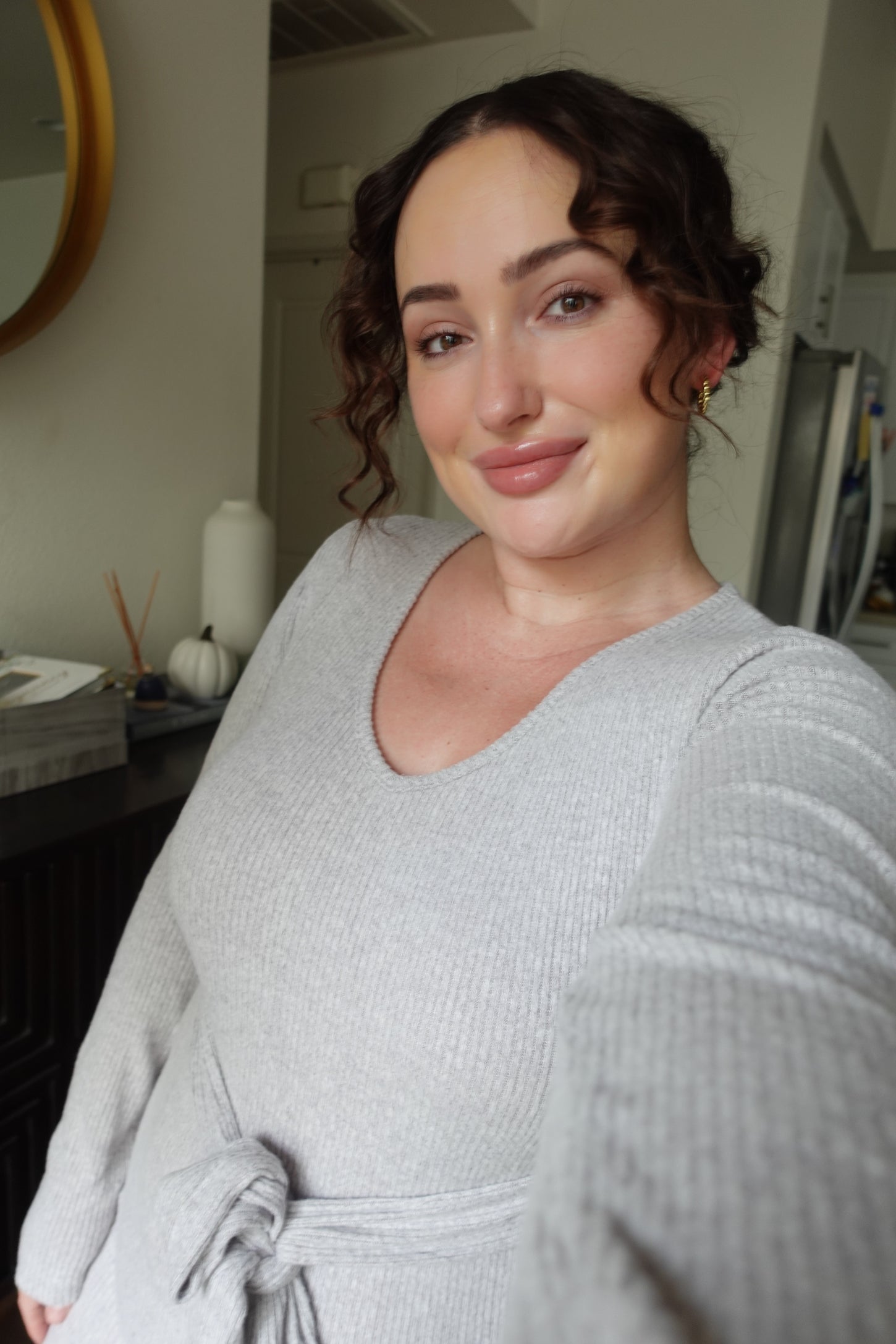 woman wearing a light gray ribbed sweater dress with a tie waist detail and a scoop neckline