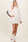 woman wearing a cream and brown color-block sweater dress with long sleeves and a mock neck, styled with white sneakers