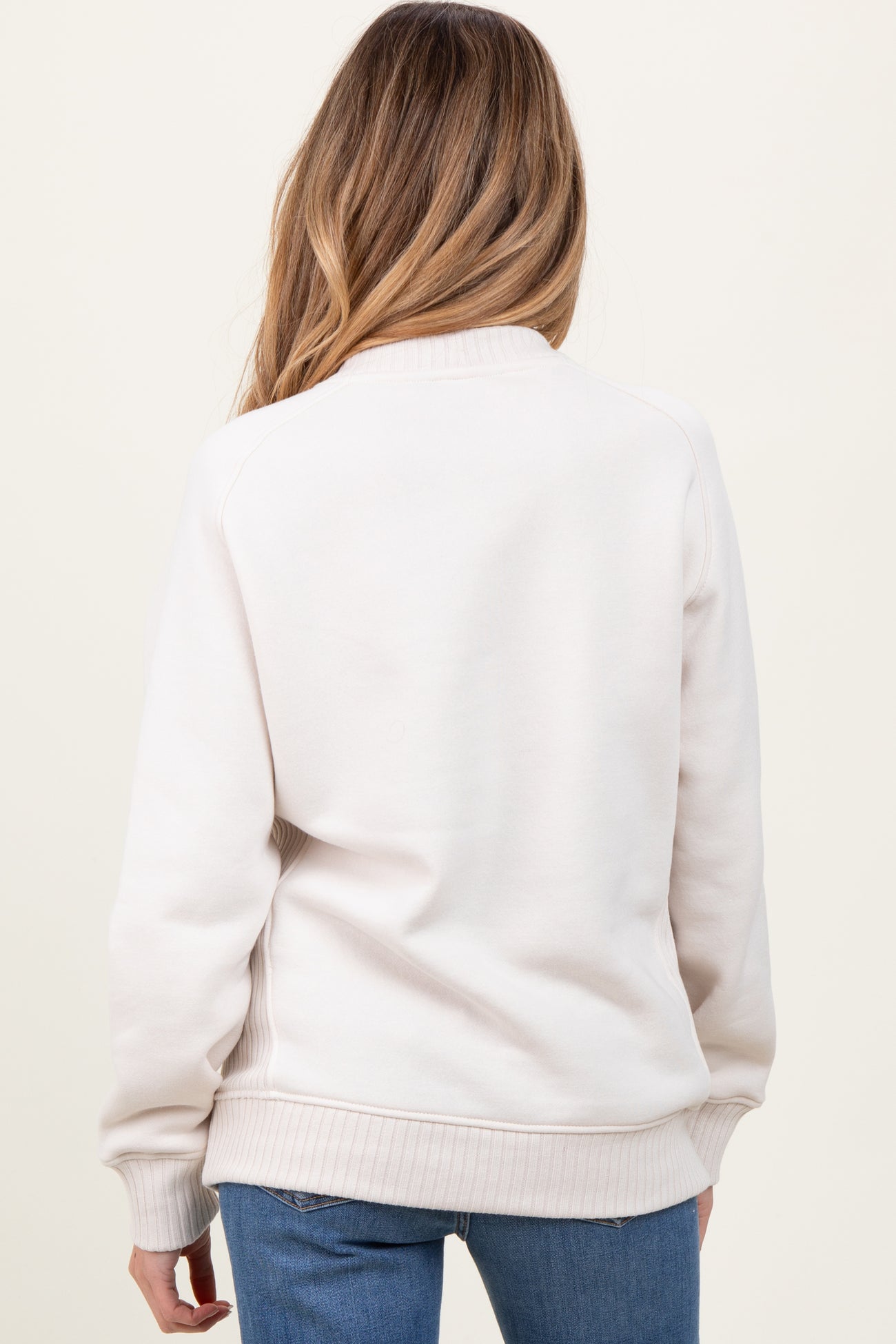 woman wearing a light beige maternity sweatshirt with a cozy fit, viewed from the back