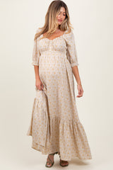 woman wearing a cream floral maternity maxi dress with puff sleeves and a tiered skirt, featuring a visible baby bump