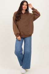 woman wearing a brown oversized pullover sweatshirt with a collar and wide-leg blue jeans