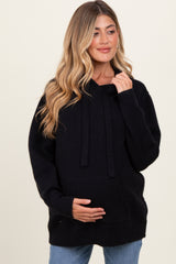 woman wearing a black maternity oversized hoodie and holding her baby bump