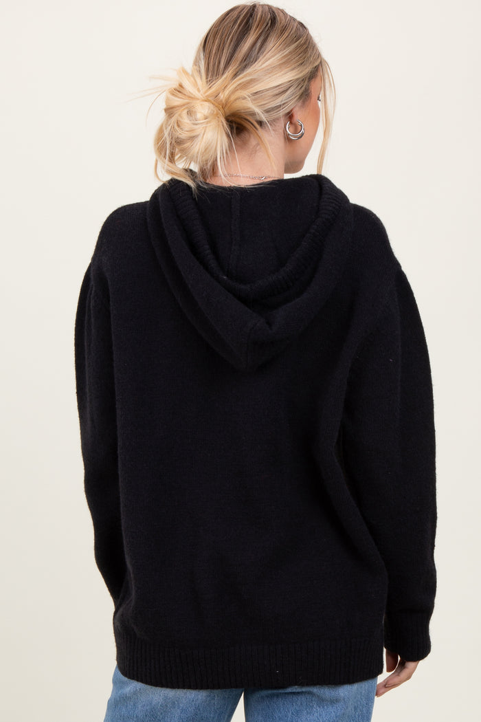 woman wearing a black oversized hoodie with a relaxed fit and a hood, shown from the back