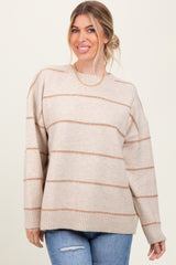 woman wearing a beige oversized sweater with brown horizontal stripes and blue jeans