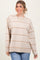 woman wearing a beige oversized sweater with brown horizontal stripes and blue jeans
