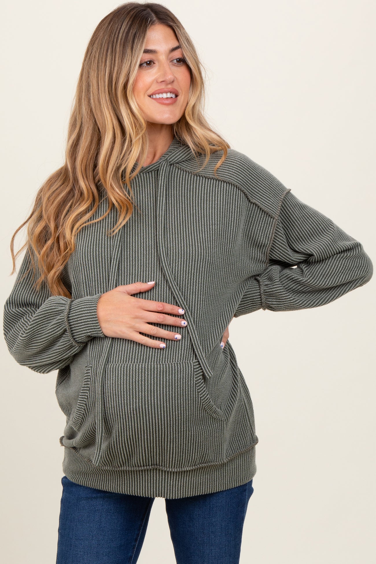 woman wearing a green ribbed maternity hoodie and holding her baby bump