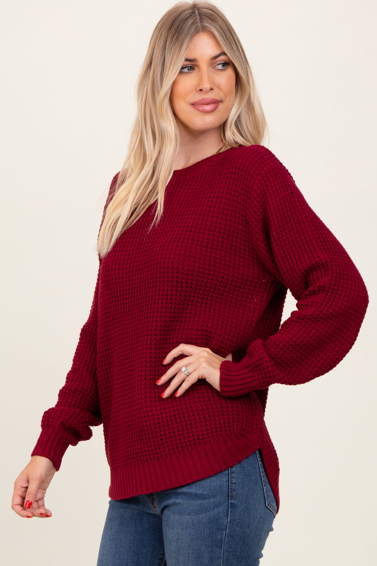 woman wearing a burgundy textured knit sweater with balloon sleeves and a relaxed fit paired with blue jeans