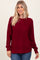 woman wearing a burgundy knit sweater with a textured design and relaxed fit, paired with blue jeans