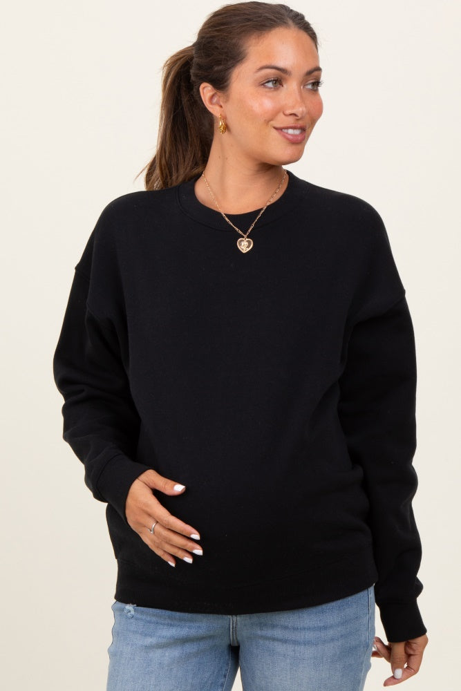woman wearing a black oversized maternity sweatshirt and holding her baby bump