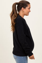 woman wearing a black maternity sweatshirt with a visible baby bump and styled hair in a ponytail