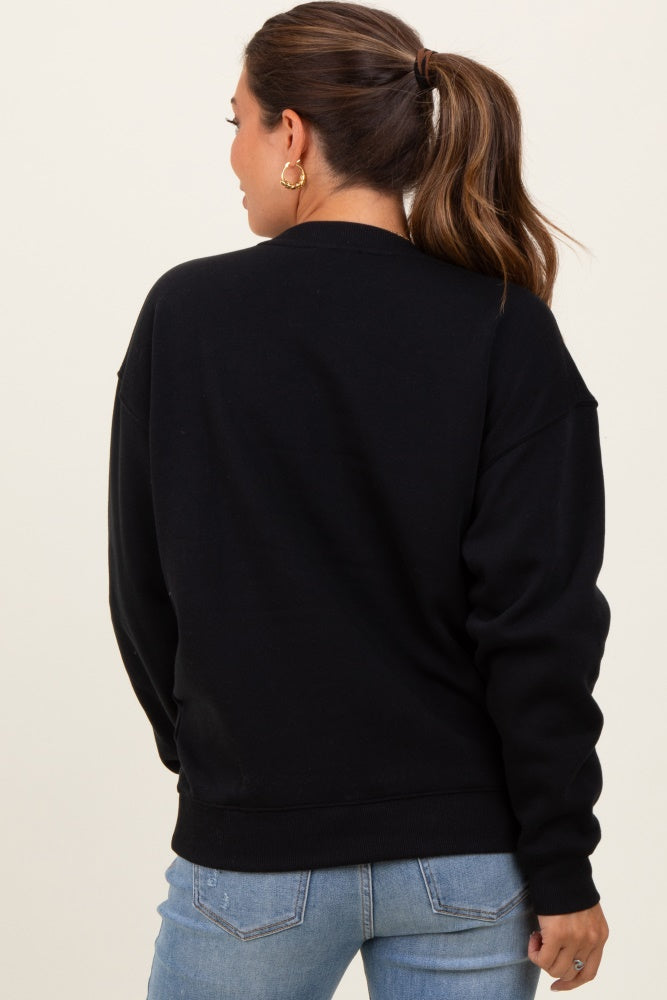 woman wearing a black oversized maternity sweatshirt, shown from the back, paired with light blue jeans