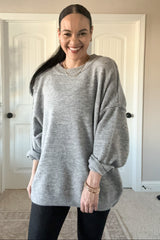 woman wearing a light gray oversized sweatshirt with dropped shoulders and styled with black leggings