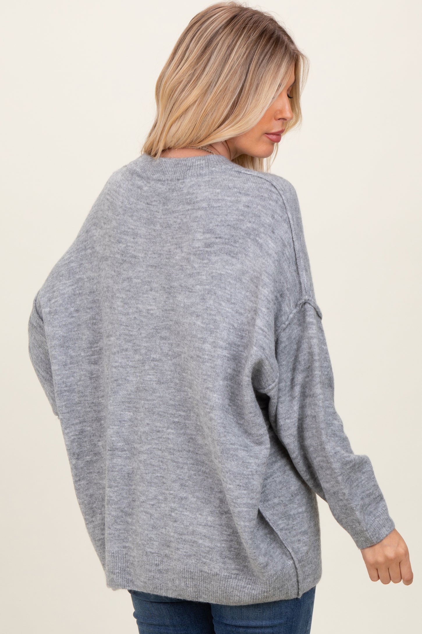 woman wearing a gray oversized sweater with dropped shoulders and a relaxed fit, viewed from the back