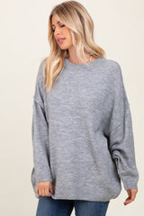 woman wearing a light gray oversized sweater with dropped shoulders and a relaxed fit, styled with blue jeans