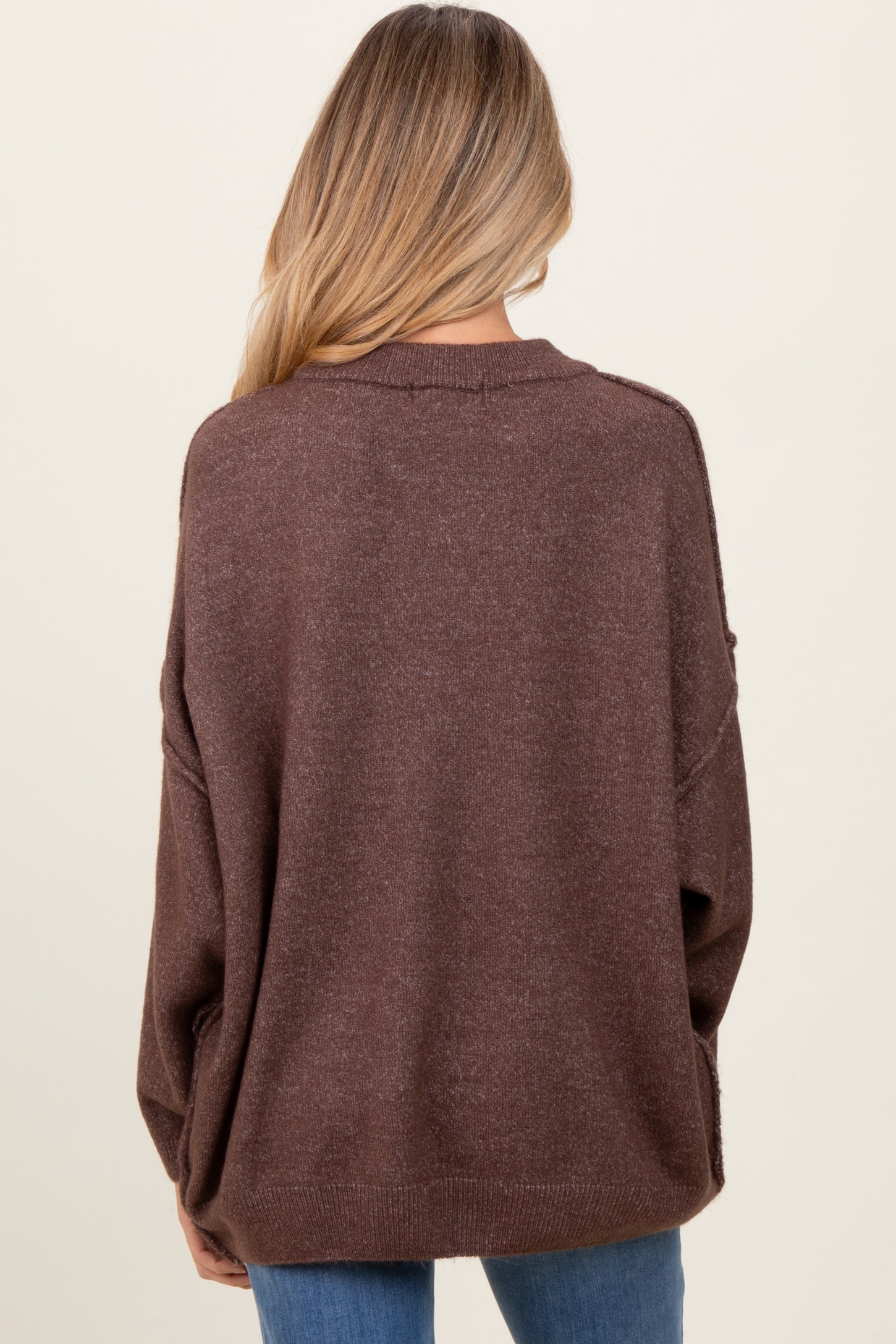 woman wearing a brown oversized maternity sweater, view from the back