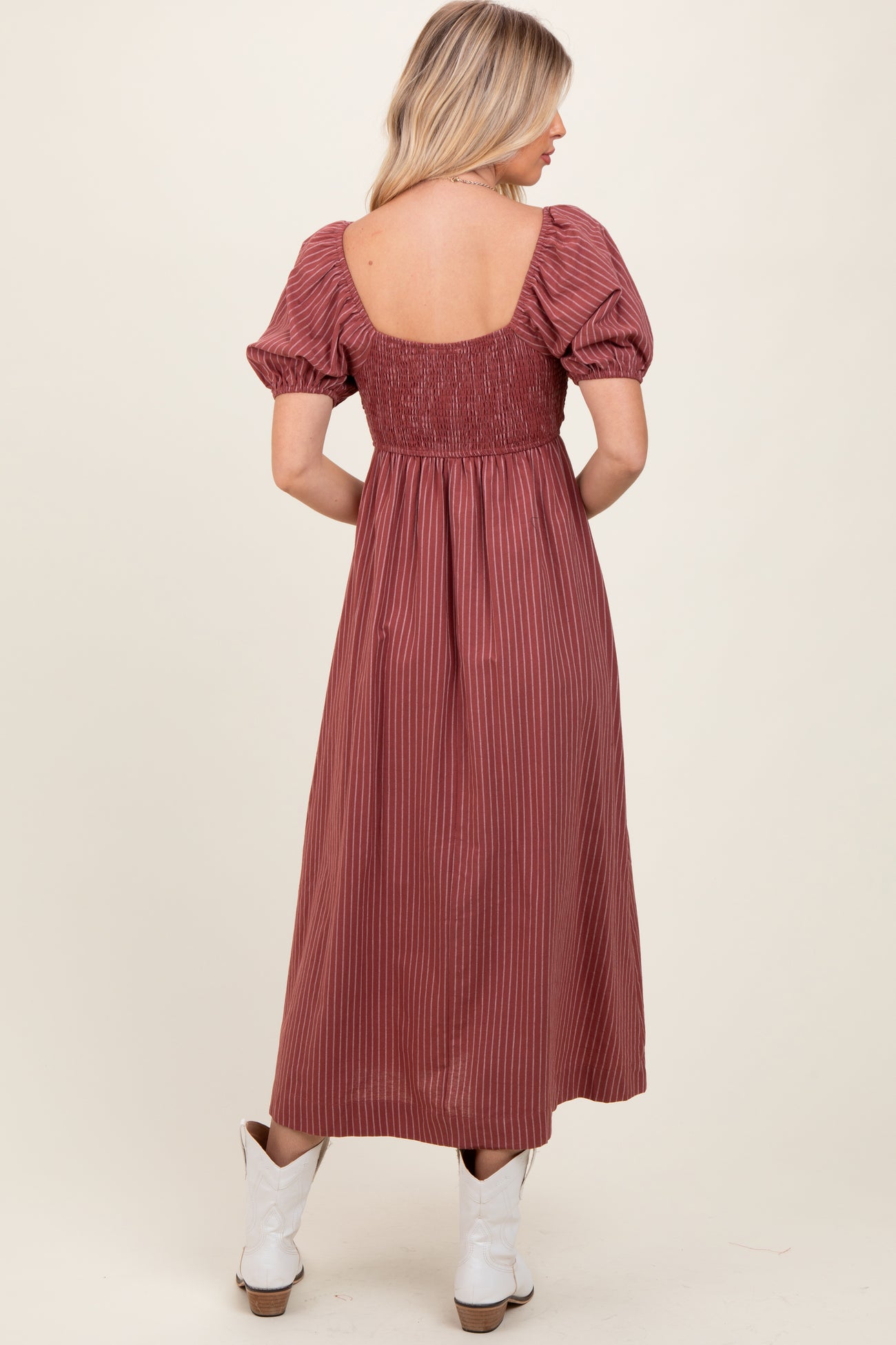 woman wearing a rust striped maxi dress with puff sleeves and a square neckline, viewed from the back