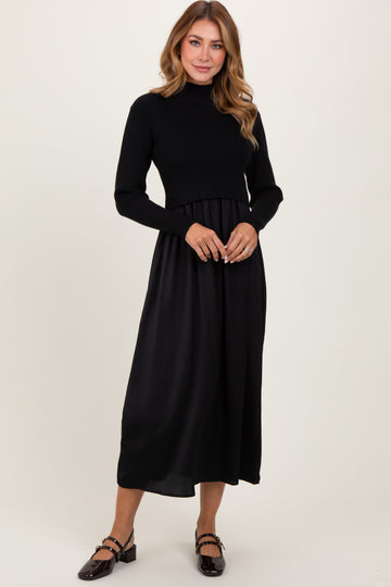 woman wearing a black knit long sleeve dress with a flowy satin skirt and flat shoes