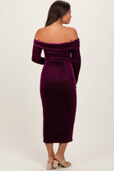 woman wearing a plum off-the-shoulder maternity dress with long sleeves and a fitted silhouette, showing her baby bump