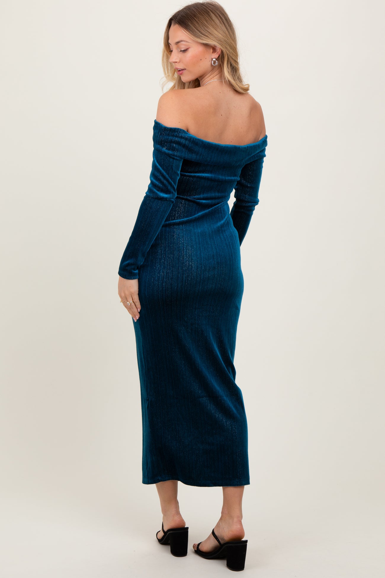 woman wearing a teal off-the-shoulder satin maxi dress with long sleeves and a fitted silhouette