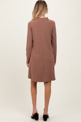 woman wearing a brown long sleeve maternity dress, shown from the back, with a relaxed fit and above-the-knee length