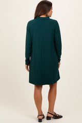 woman wearing a dark green long sleeve maternity dress, seen from the back