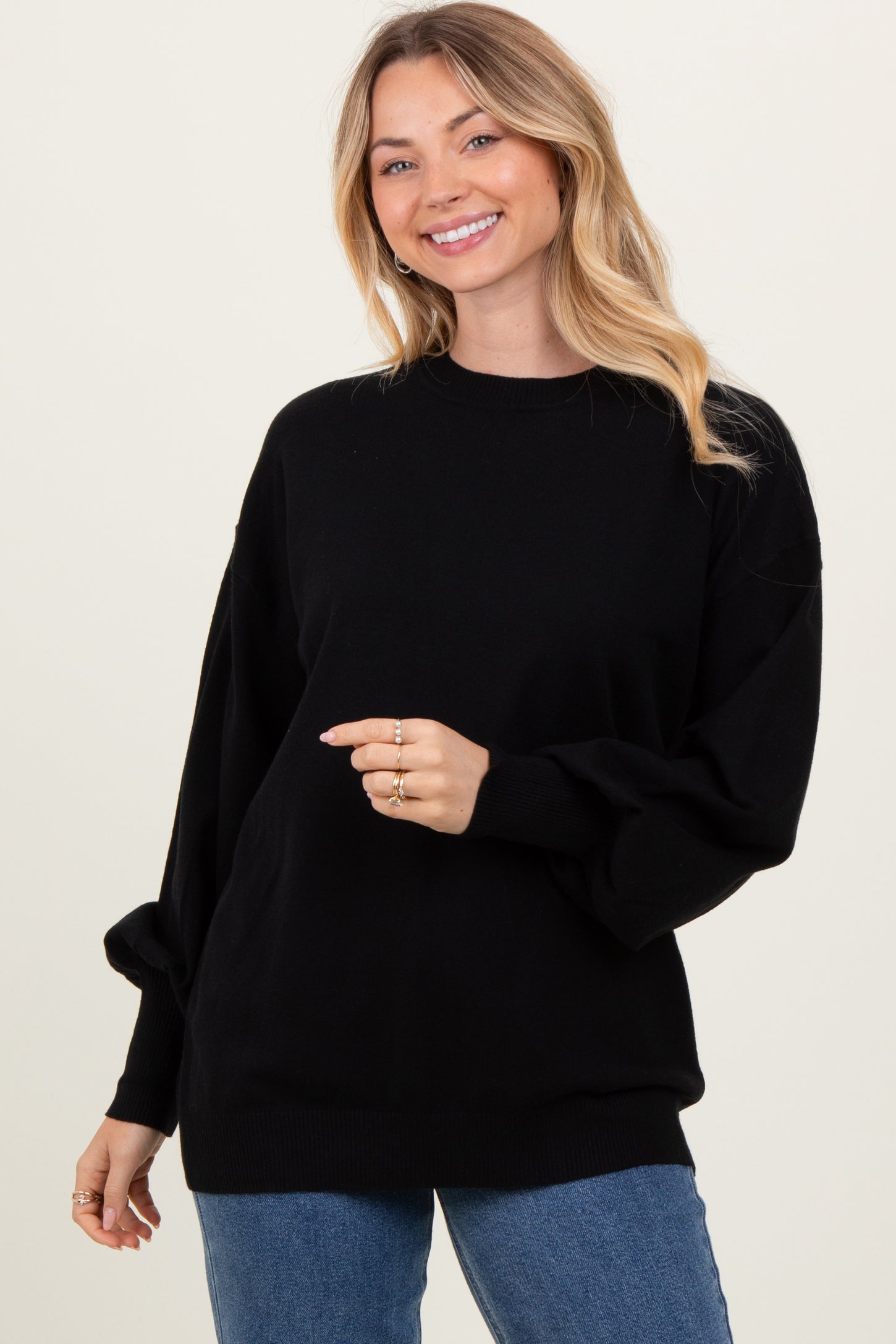 woman wearing a black oversized sweater with long sleeves and a relaxed fit, smiling at the camera