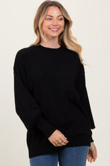 woman wearing a relaxed fit black oversized sweater with long sleeves and a round neckline, smiling