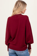 woman wearing a burgundy oversized sweater with balloon sleeves and a ribbed hem, seen from the back