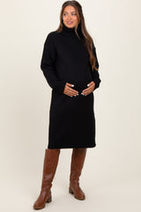 woman wearing a black turtleneck maternity sweater dress and holding her baby bump