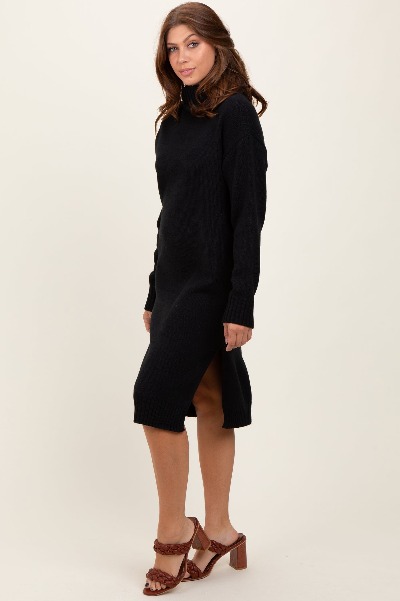 woman wearing a black long sleeve knit sweater dress with side slits and brown heeled sandals