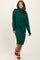 woman wearing a green turtleneck sweater dress with long sleeves and a relaxed fit, paired with brown strappy sandals
