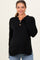 woman wearing a black maternity henley sweater with buttons and side slits, smiling at the camera