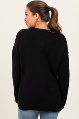 woman wearing a black oversized maternity sweater with long sleeves, viewed from the back
