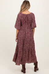 woman wearing a burgundy floral maternity maxi dress with short puff sleeves and a tiered skirt, showing the back view