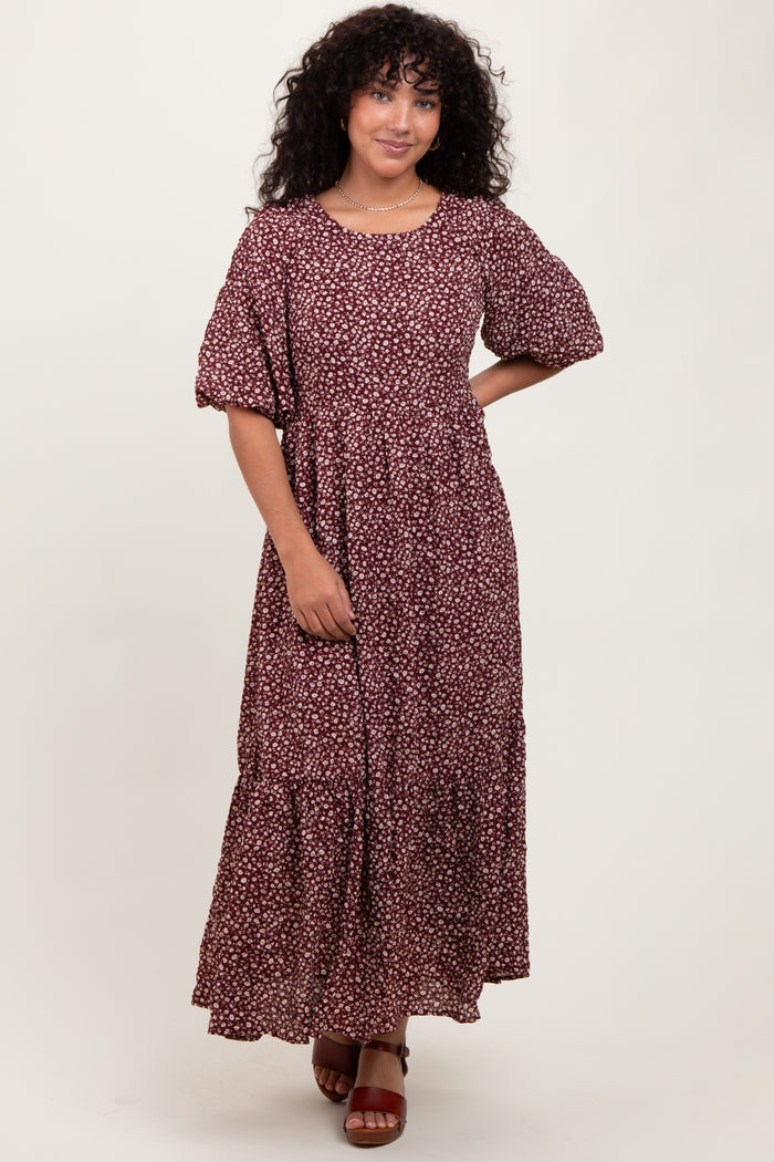 woman wearing a burgundy floral maxi dress with puff sleeves and a tiered skirt