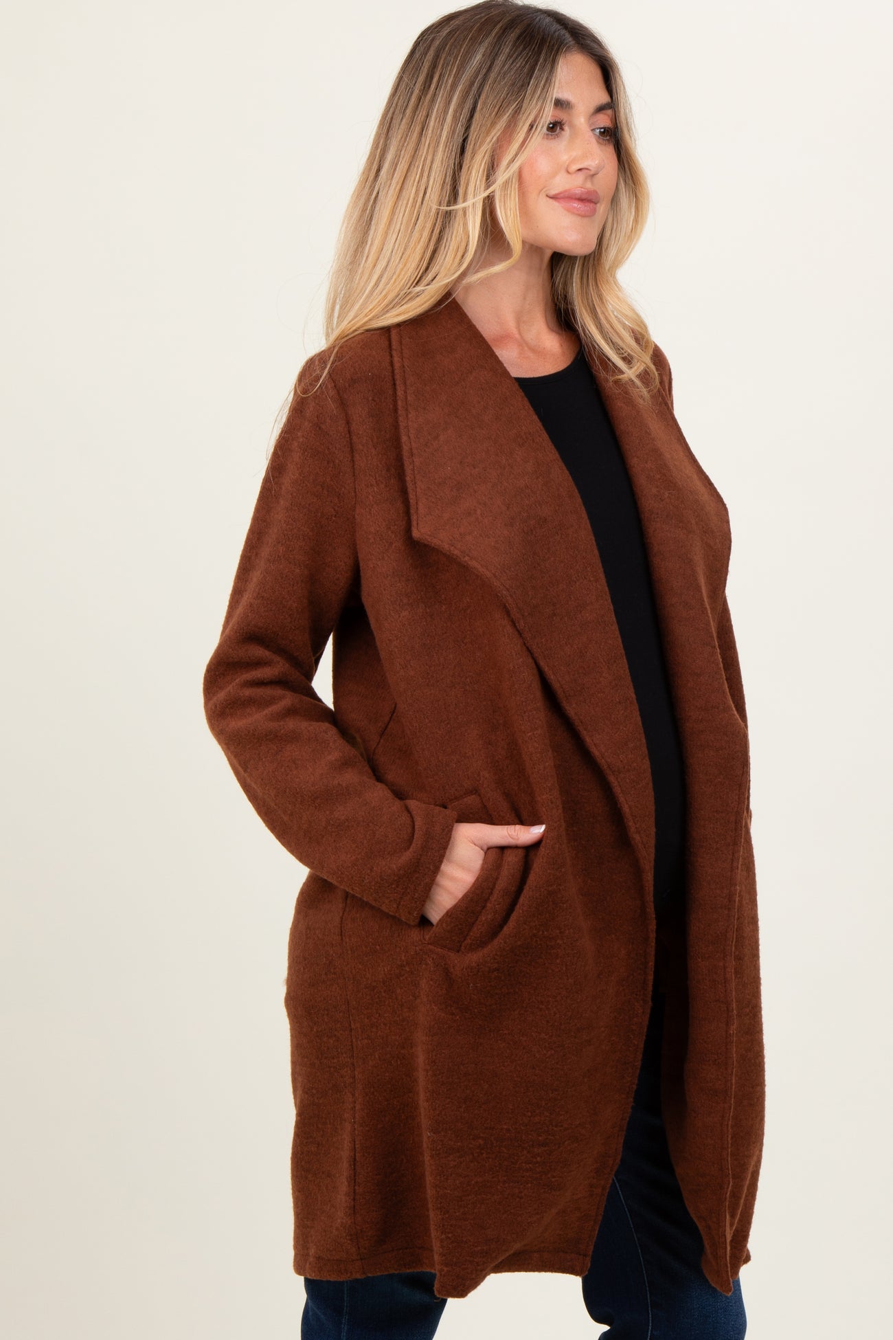 woman wearing a brown long open front maternity cardigan with pockets and a visible baby bump