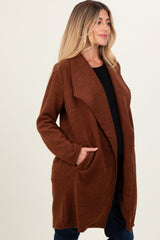 woman wearing a brown long open front maternity cardigan with pockets and a visible baby bump