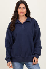 woman wearing a navy blue oversized fleece pullover with a collar and button details, paired with light wash jeans