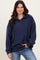 woman wearing a navy blue oversized fleece pullover with a collar and long sleeves, styled with light blue jeans