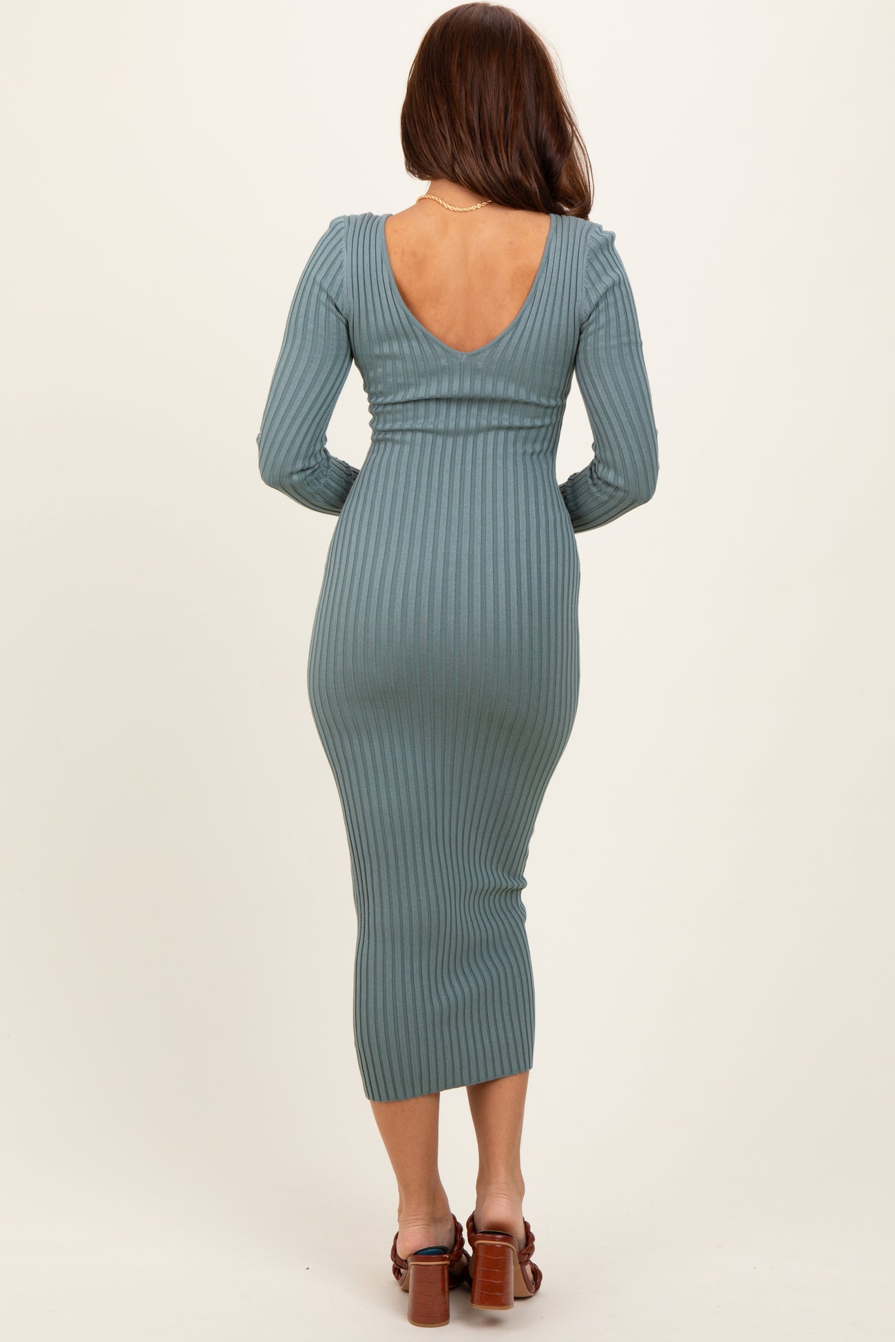 woman wearing a teal ribbed long sleeve midi dress with a low back and fitted silhouette