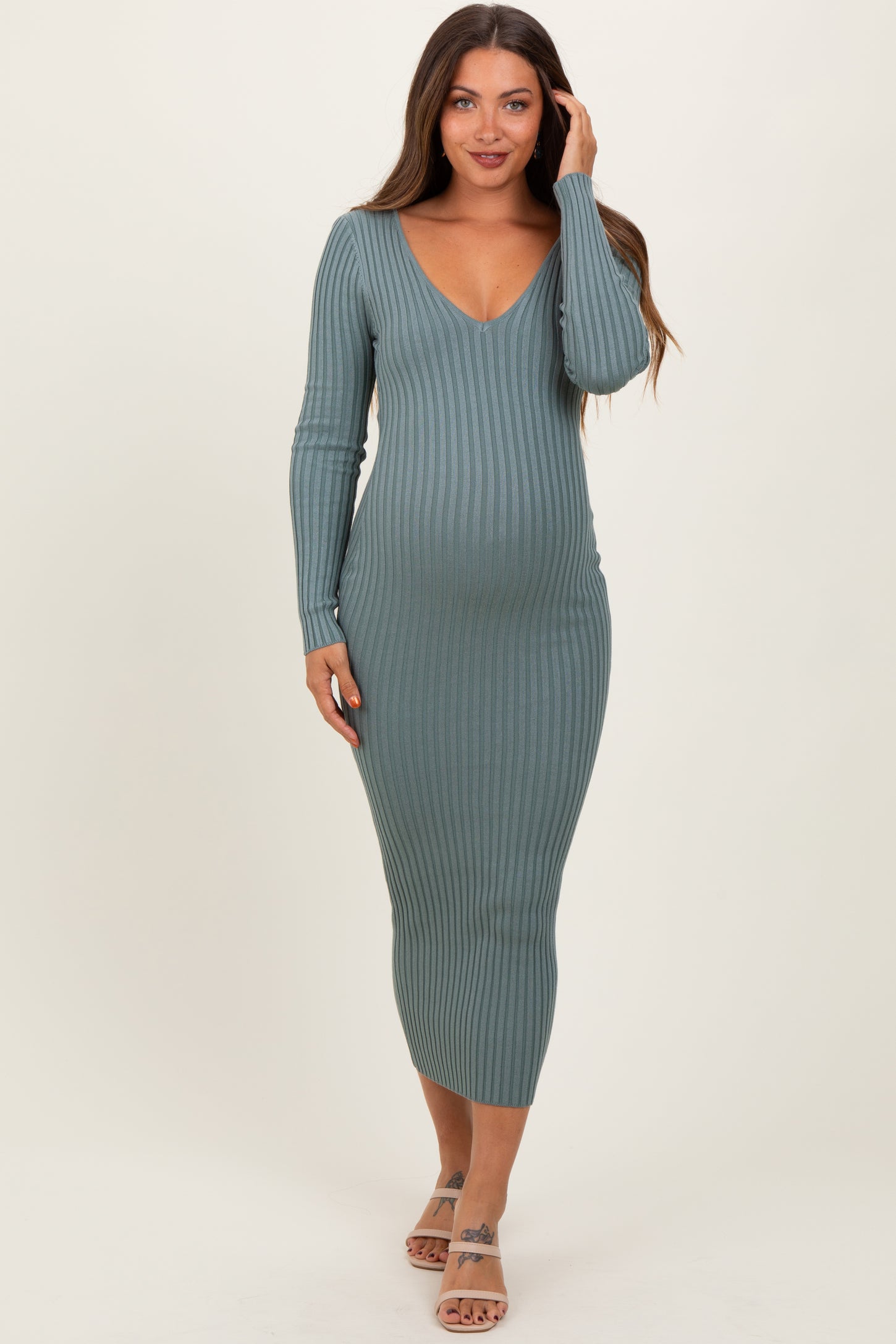 woman wearing a green ribbed long sleeve maternity dress and showing her baby bump