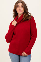 woman wearing a bright red knitted sweater with a cowl neck and side slits, paired with blue jeans
