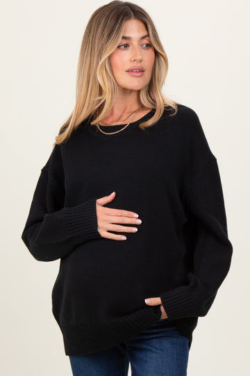 woman wearing a black oversized maternity sweater and holding her baby bump
