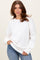 woman wearing a white oversized sweater with ribbed hem and long sleeves paired with blue jeans