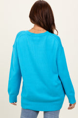 woman wearing a back view of a bright blue oversized sweater with ribbed cuffs and hem