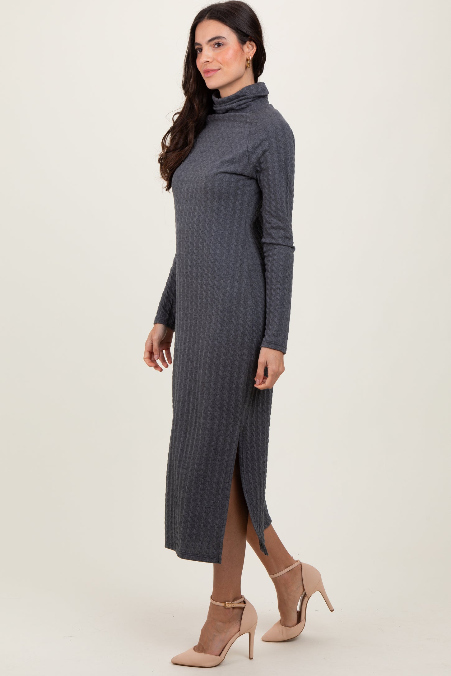 woman wearing a dark gray long sleeve midi dress with a turtle neck and side slit, styled with beige high heels