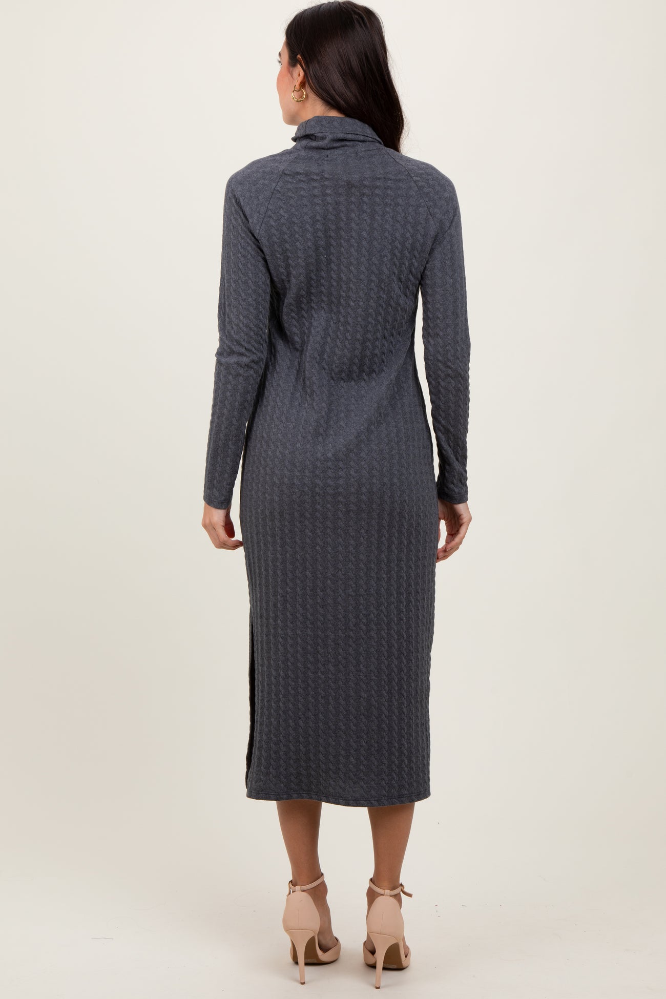 woman wearing a long gray sweater dress with a fitted silhouette and side slits, viewed from the back